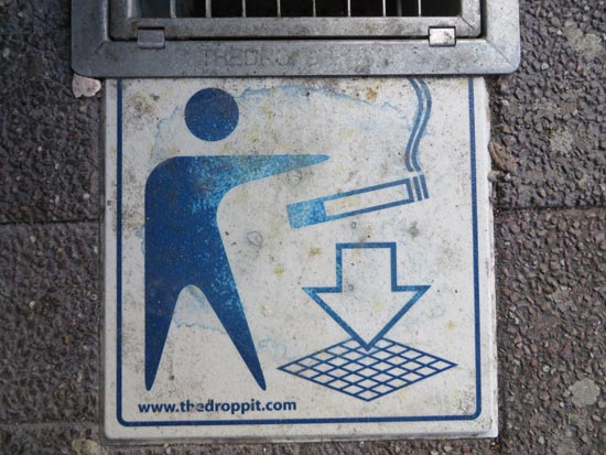 tegel met pictogram van poppetje die sigaret in een rooster gooit